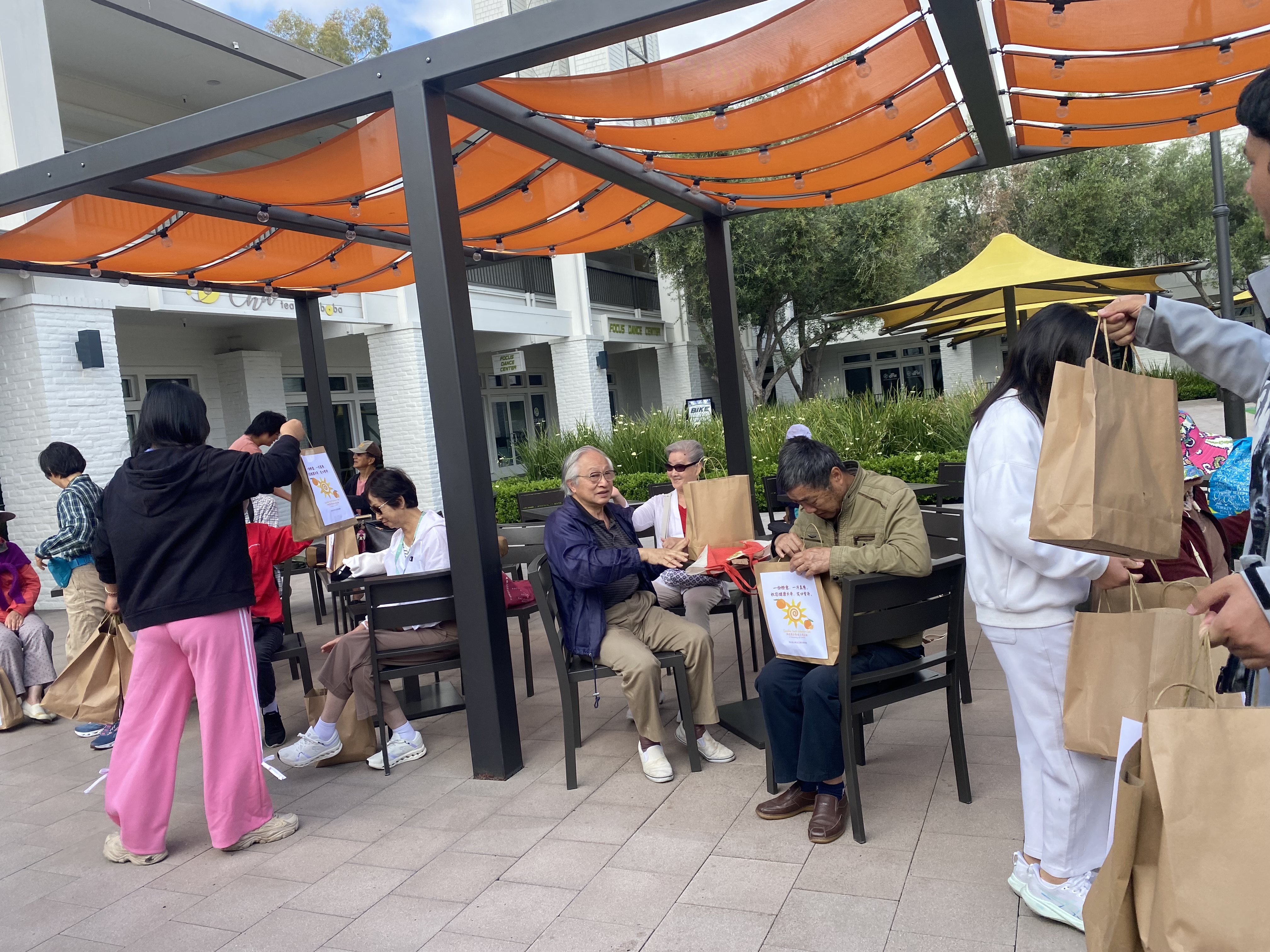 Children distributing orange gift bags to seniors